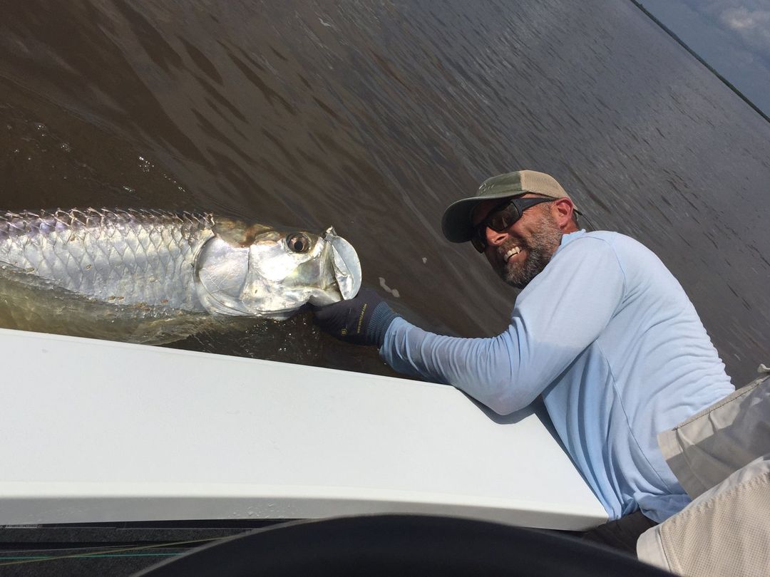 Captain Scott Dykes releasing a tarpon boatside