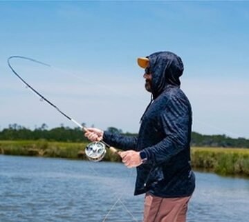 Angler fly casting along the marsh
