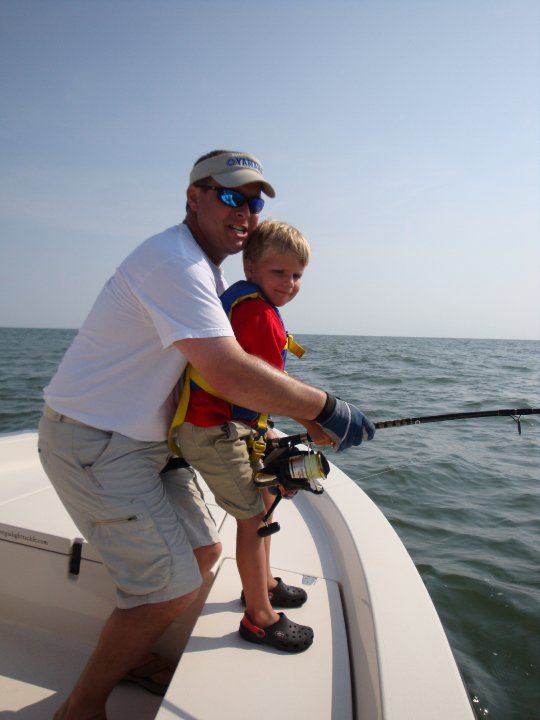Father helping his son reel in a fish