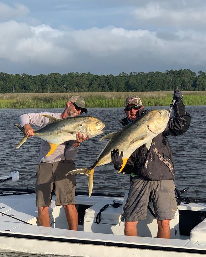 Two anglers holding jack crevalle